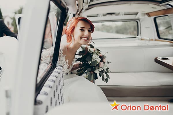 Stock image of a bride smiling from inside a car while holding a bouquet