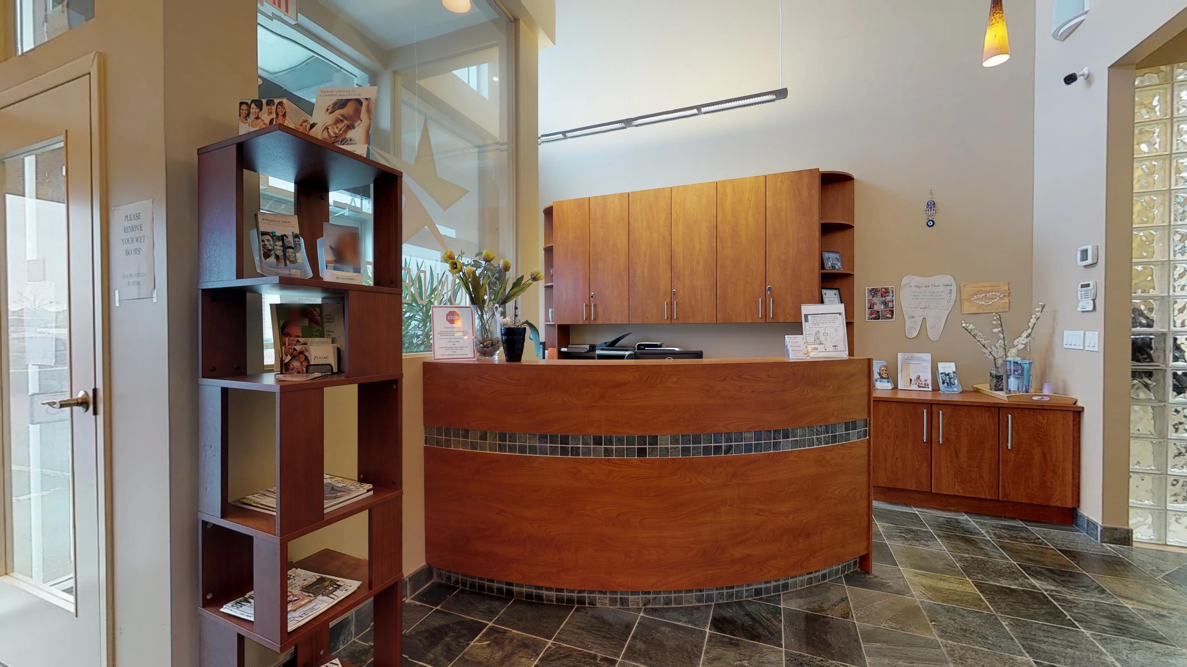 The reception area at Orion Dental Milton, with a curved wood front desk and slate tile floor